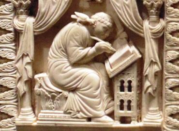 Ivory carving of a man bent over a desk, writing