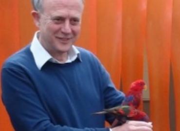 Christopher Martin holding a bright red bird